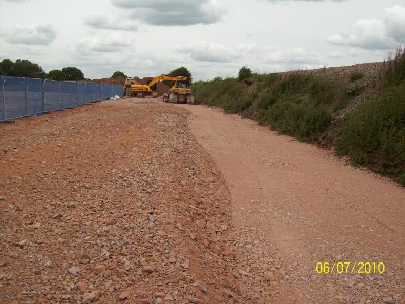 Stone being placed and compacted along the bottom of the embankment 