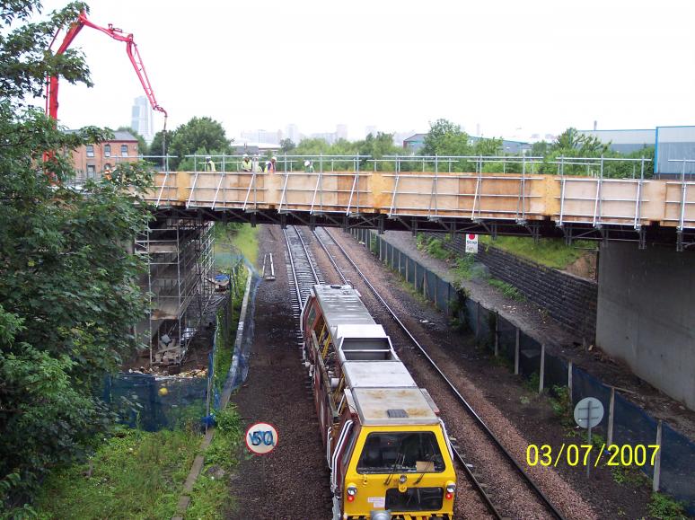 Concrete pump placing concrete on the bridge deck with the track open below.