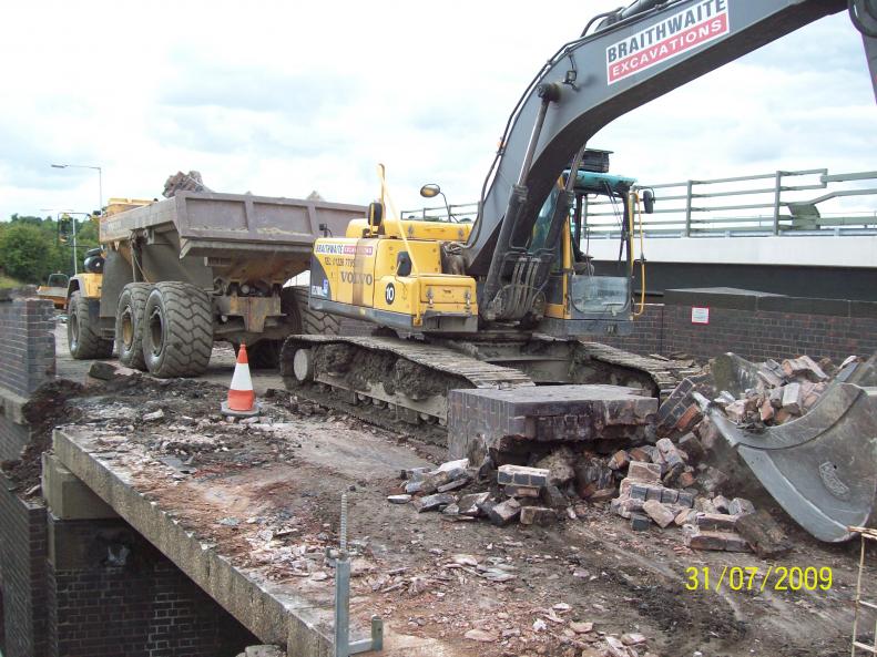 Excavator on the deck clearing parapet.