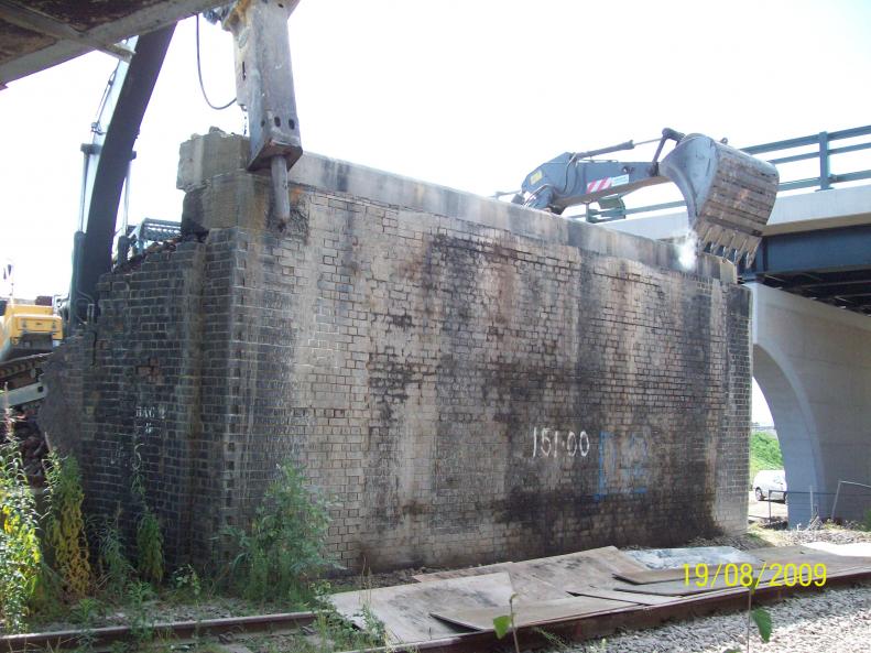 Concrete capping beam being pulled off by two excavators